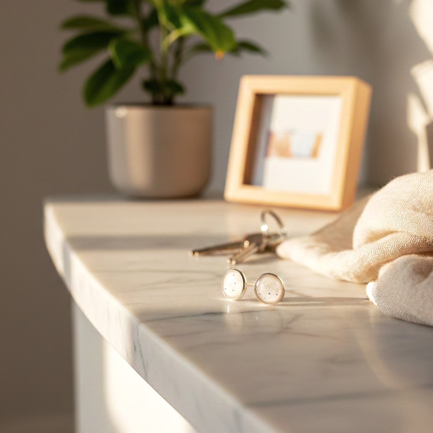 Round earrings on a marble surface with a plant and framed picture in the background