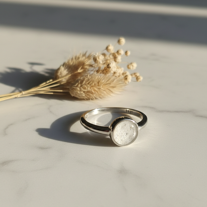 Silver ring on a marble surface with dried flowers