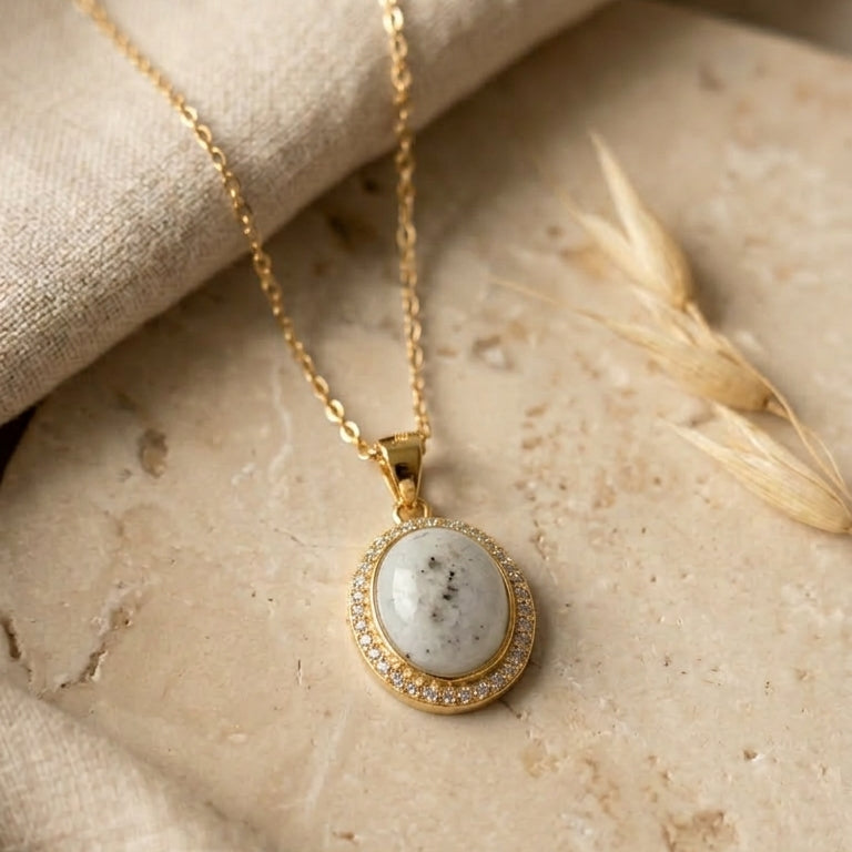gold necklace with a pendant on a stone surface