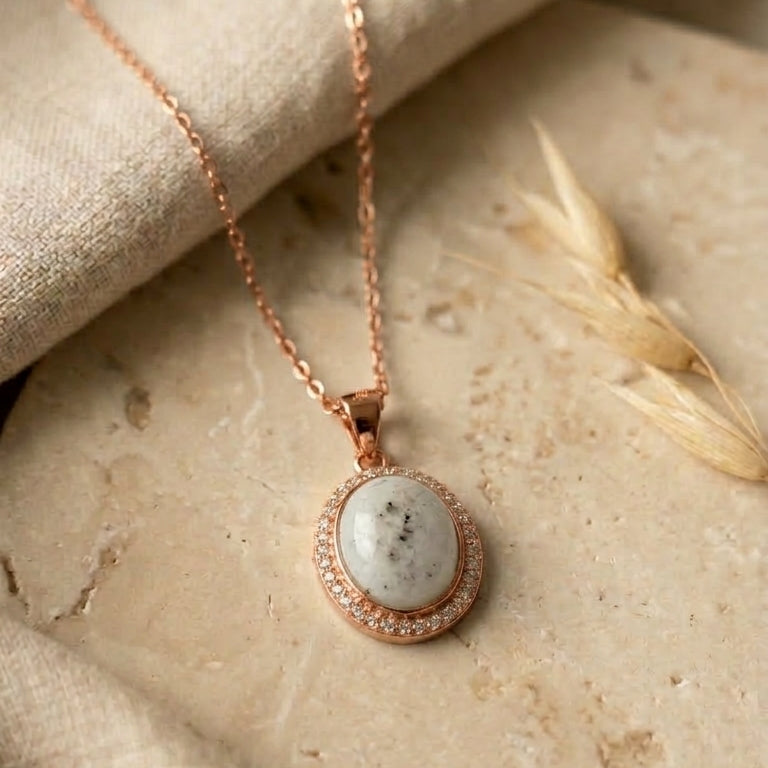 Rose gold necklace with a pendant on a stone surface