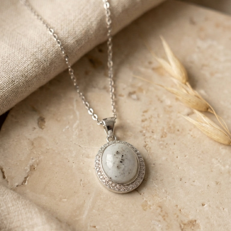 silver necklace with a pendant on a stone surface