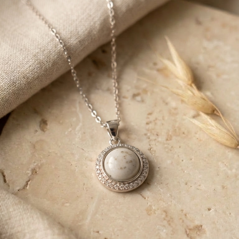 Silver necklace with a round pendant on a stone surface