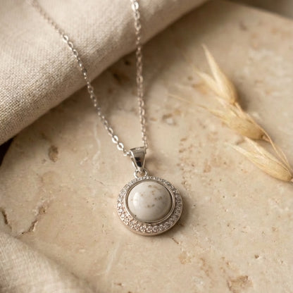 Silver necklace with a round pendant on a stone surface
