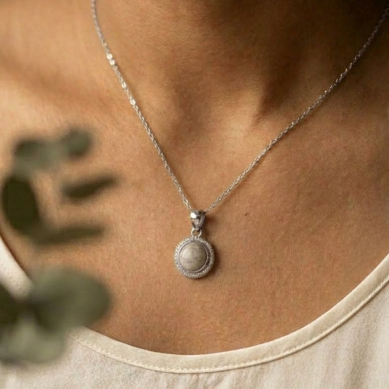 silver necklace with a pendant worn by a person