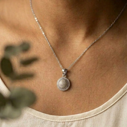 silver necklace with a pendant worn by a person